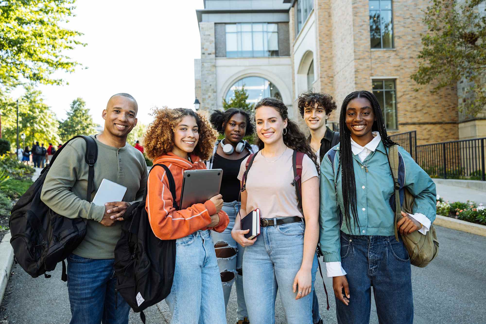 group of diverse high school students posing in front of school